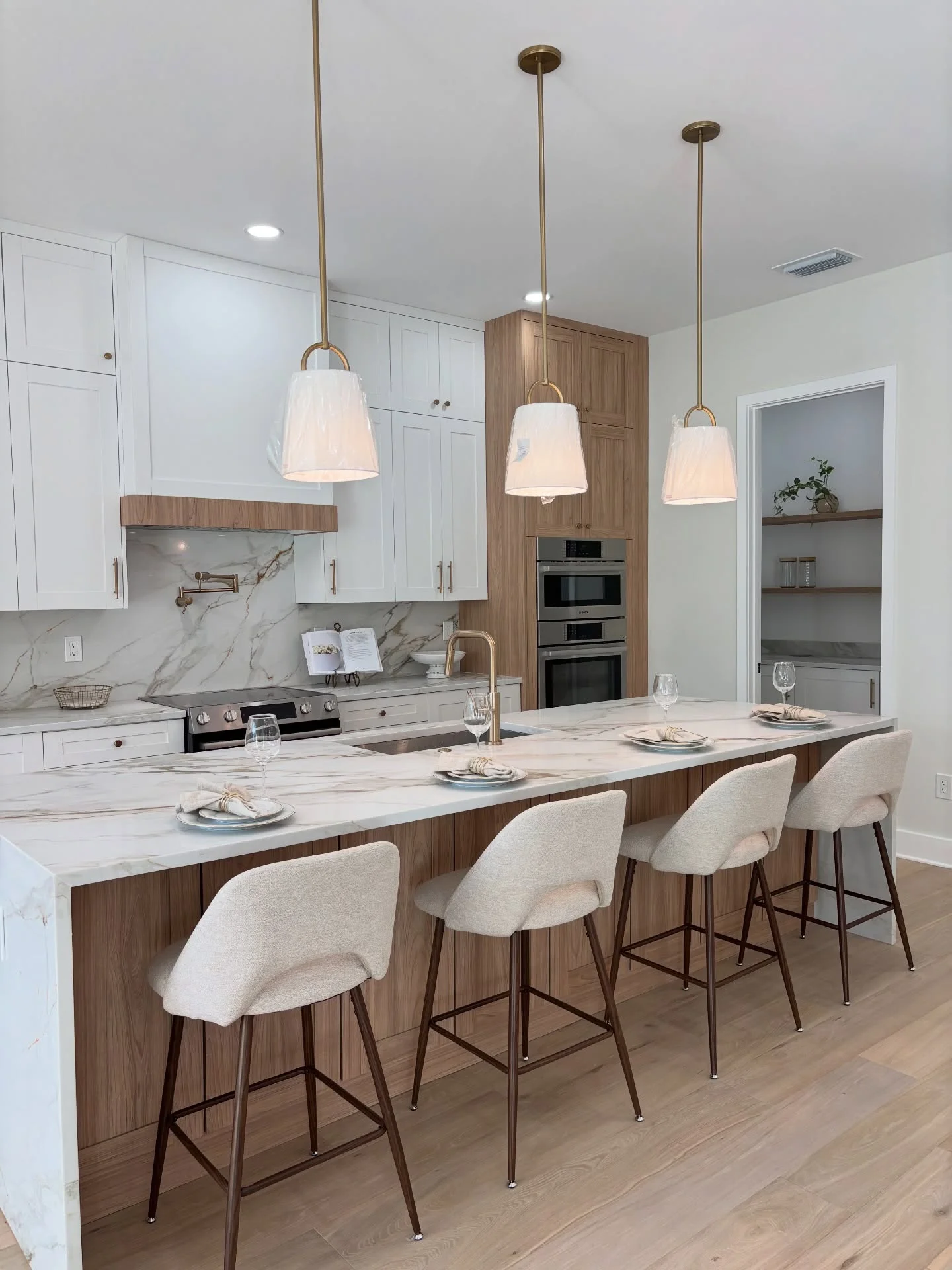 Light wood and white kitchen styled with upholstered stools and inviting place settings