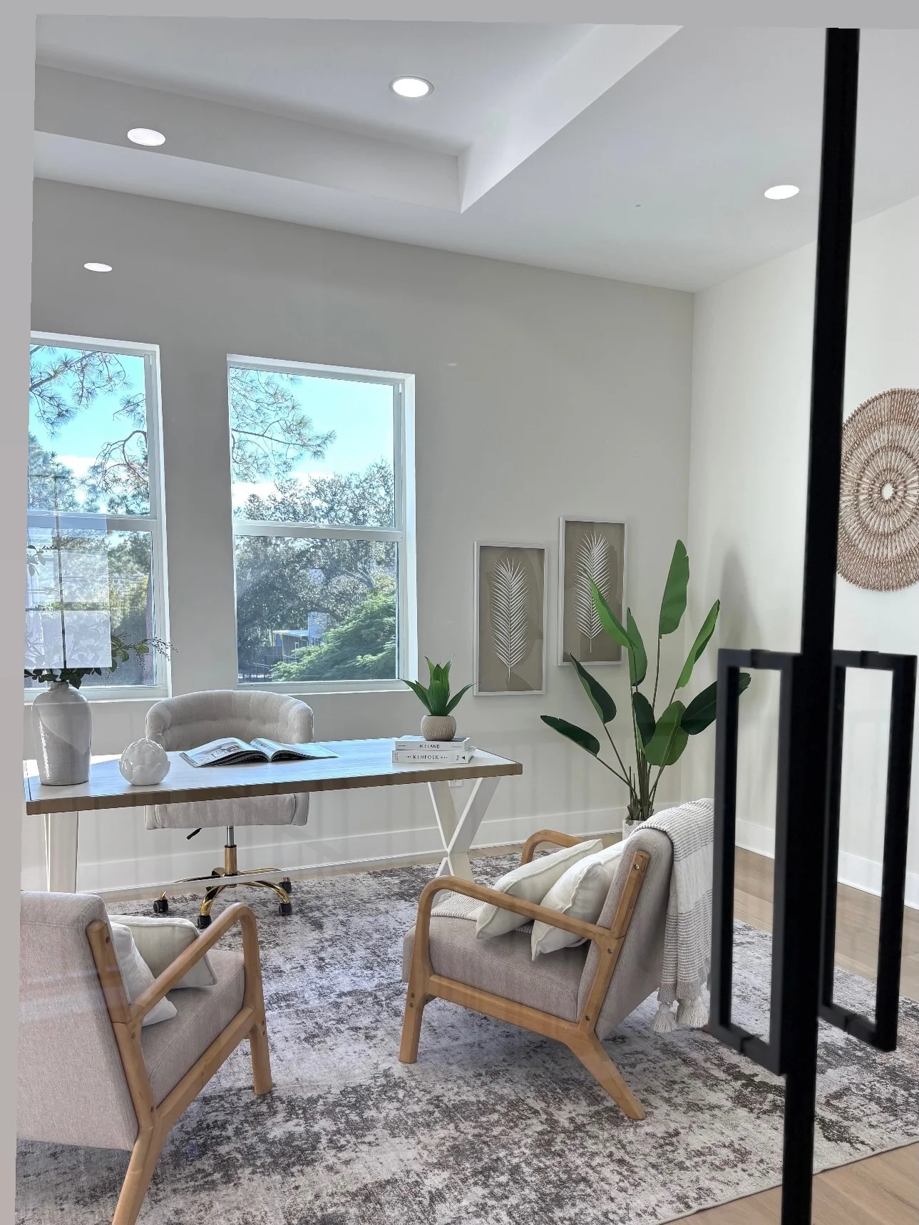 Bright home office staged with a desk, accent chairs and natural greenery